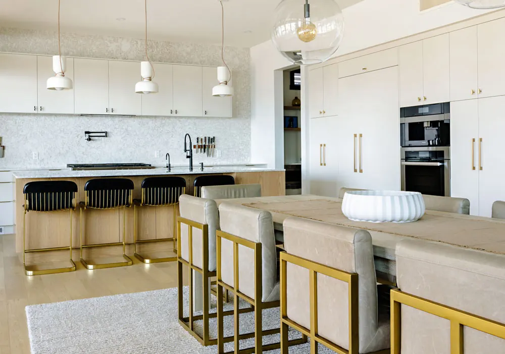 Open-plan kitchen and dining room with white oak island, brass-framed stools, and marble backsplash by Amend Developments