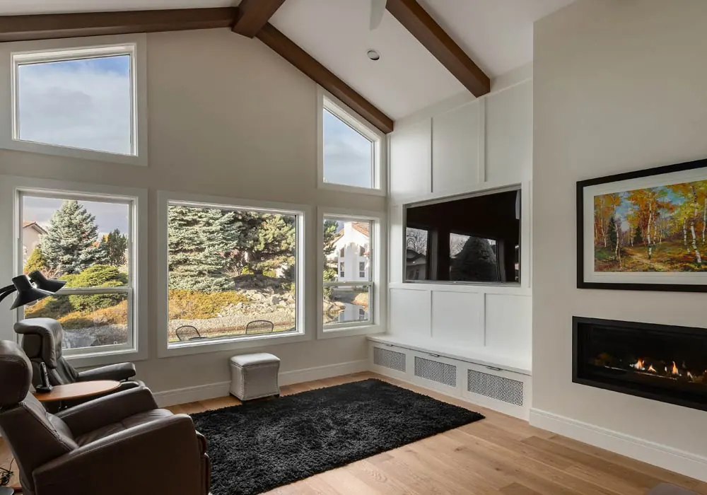 Vaulted great room with exposed beams, a wall of windows, and a linear fireplace by Amend Developments